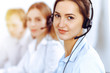 © rogerphoto - Call center operators. Focus on beautiful business woman using headset in sunny office