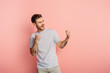© LIGHTFIELD STUDIOS - excited young man showing winner gesture while looking away on pink background