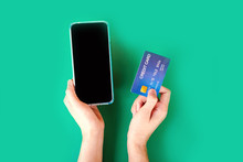 Online Shopping Concept With Woman Hand Holding Smart Phone And Credit Card Top View On Green Background 