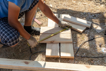 Worker measures a wooden board at a construction site