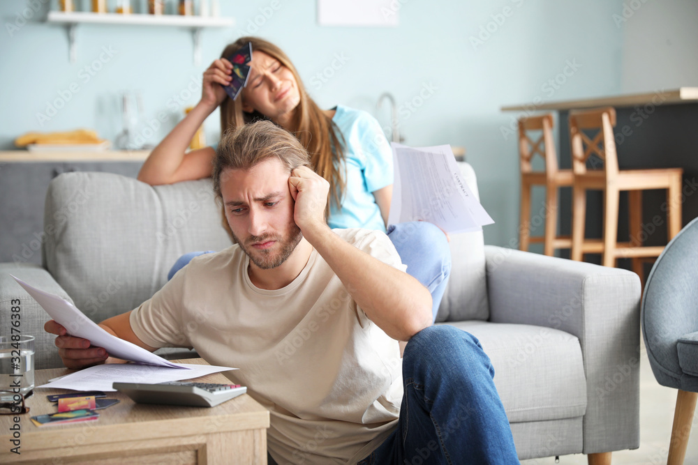 Worried young couple in debt at home