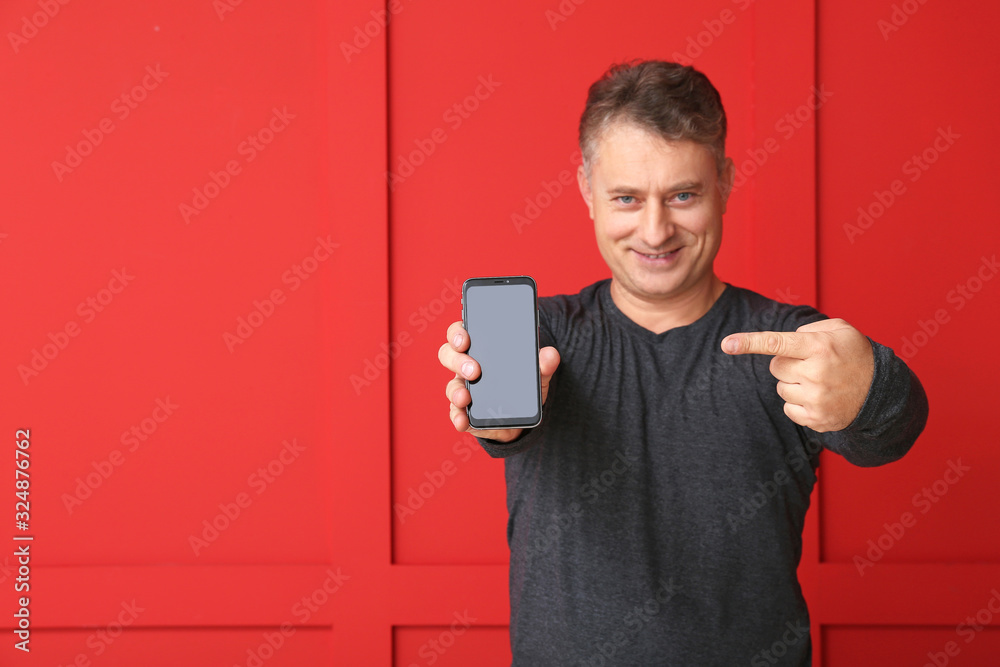 Happy mature man with mobile phone on color background