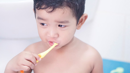 Cute funny little Asian kid 2 year old. Toddler boy, child do not wear a shirt. He holding toothbrush and doing brushing his teeth. Tooth care for children concept.                                    