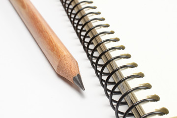 Single wooden pencil lying near the blank diary page, macro shot with selective focus