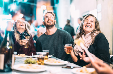 Happy friends having fun drinking white wine at street festival - Young people eating local food at open air restaurant together - Dinning lifestyle concept on string light neon filter