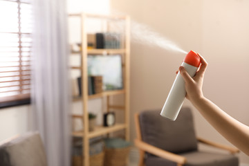 Wall Mural - Woman spraying air freshener at home, closeup