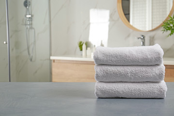 Poster - Stack of clean towels on grey stone table in bathroom. Space for text