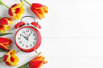 Poster - Red alarm clock, spring flowers and space for text on white wooden table, flat lay. Time change