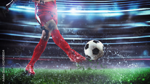 Football scene at night match with player in a red uniform kicking the ball with Tableau sur Toile
