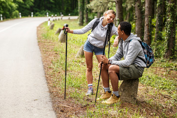 Wall Mural - young couple hiking in nature.they sitting and resting by the old country road.