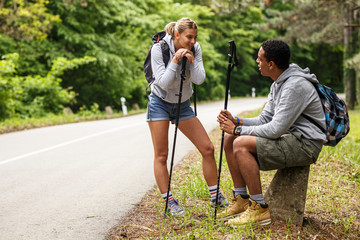 Wall Mural - young couple hiking in nature.they sitting and resting by the old country road.