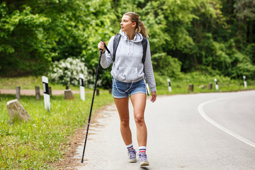 Wall Mural - young blond hair female hiking by the road.