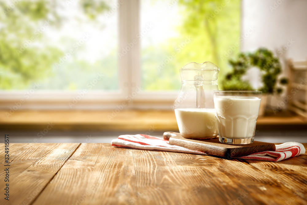 Fresh cold milk on wooden table and kitchen interior.Spring sunny day and free space for your decoration.  - obrazy, fototapety, plakaty 
