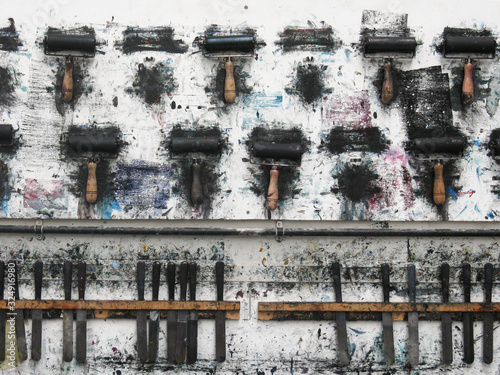 Fotomural Printmaking rollers hanging on an art studio wall in the messy workshop