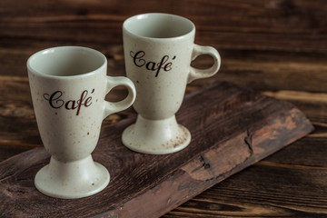 two cups on brown wooden plank on table