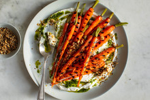 Overhead View Of Grilled Carrots Served With Hazelnut Dukkah, Yogurt And Carrot Top Oil On Plate
