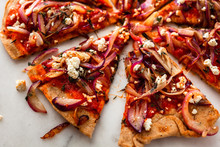 Close Up View Of Sliced Pizza With Grilled Red Onions And Feta