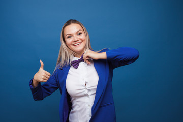 Wall Mural - Funny business lady in a blue jacket and purple bow tie. jumps for joy and gives a thumbs up.