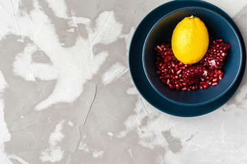 yellow lemon with red pomegranate seeds in a blue bowl on a blue plate