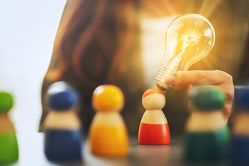 Wall Mural - closeup image of a woman holding and putting a light bulb over one of a different colors wooden peop