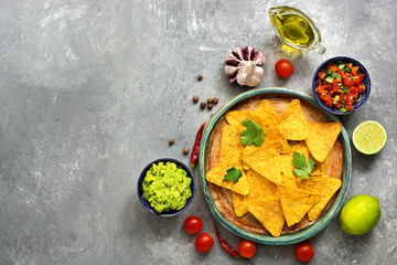 Wall Mural - Traditional mexican snack nachos in a plate with guacamole and salsa sauce on a gray concrete background. Top view, flat lay, copy space.