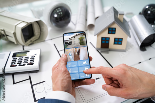 Cuadros en Lienzo Person Hand Using Home Security System On Mobilephone