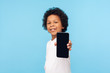 © khosrork - Positive adorable happy little boy with curly hair smiling cute and showing mobile phone to camera, child looking excited and proud of cell phone. indoor studio shot isolated on blue background