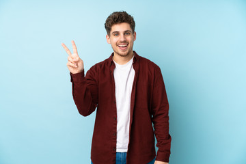 Wall Mural - Young caucasian man isolated background smiling and showing victory sign