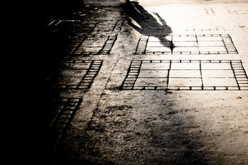 Blurry shadow silhouette on city sidewalk of mysterious man walking