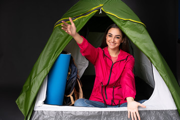 Young caucasian woman inside a camping green tent presenting and inviting to come with hand