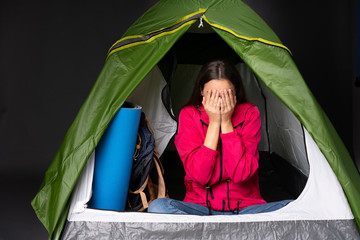 young caucasian woman inside a camping green tent with tired and sick expression