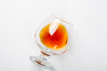 A glass of whiskey lies on its side on a white background.