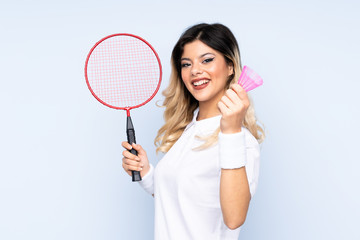 Teenager girl playing badminton isolated on blue background