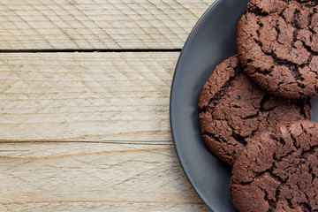 Top view, chocolate chip cookies on a black plate. wooden background. From above. copy space