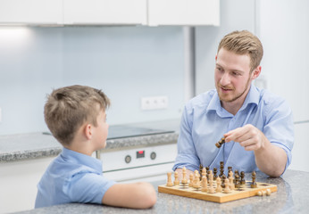 Father teaches son to play chess at home