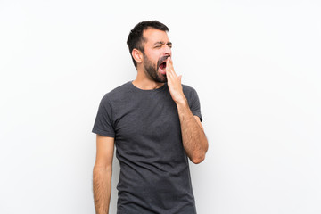 Young handsome man over isolated white background yawning and covering wide open mouth with hand