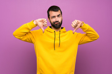 Wall Mural - Handsome man with yellow sweatshirt showing thumb down