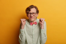 Ecstatic Male Nerd Raises Clenched Fists, Believes In Success, Closes Eyes And Awaits Announcement Of Results, Participates In Contetst, Hopes To Win, Expresses Impatience, Dressed Formally.