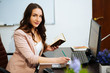 © ostap_davydiak - young business woman reading sitting at the desk on office background