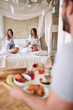 © luckybusiness - two women laughing surprised by a guy brining them breakfast in bed. lesbian, bisexual, threesome concept