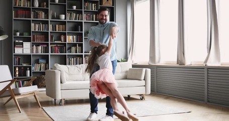 loving father having fun spinning with child daughter at home
