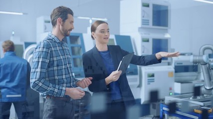 Poster - Modern Factory: Female Project Manager and Male Engineer Standing, Talking, Using Digital Tablet for Programming and Monitoring Assembly Line. Industry 4.0 Facility with High-Tech CNC Machinery