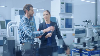 Poster - Modern Factory: Female Project Manager and Male Engineer Standing, Talking, Using Digital Tablet for Programming and Monitoring Assembly Line with Robot Arm. Industry 4.0 Facility with CNC Machinery