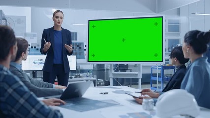 Wall Mural - Modern Industrial Factory Meeting: Confident Female Engineer Uses Interactive Green Mock-up Screen Whiteboard, Makes Report to a Group of Engineers, Managers 