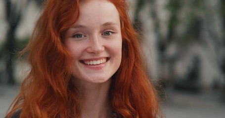 portrait of ginger girl with freckles looking into the camera and smiling