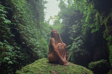 Sexy young girl in a green swimsuit in a tropical jungle. Bali.