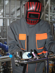 the welder in the workplace. the welder welds the pipe with argon. worker in personal protective equ