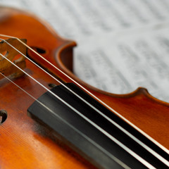 Beautiful old violin close up lying on the blurred sheet music