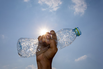  Hand squeeze plastic bottle and sun shining in the blue sky background
