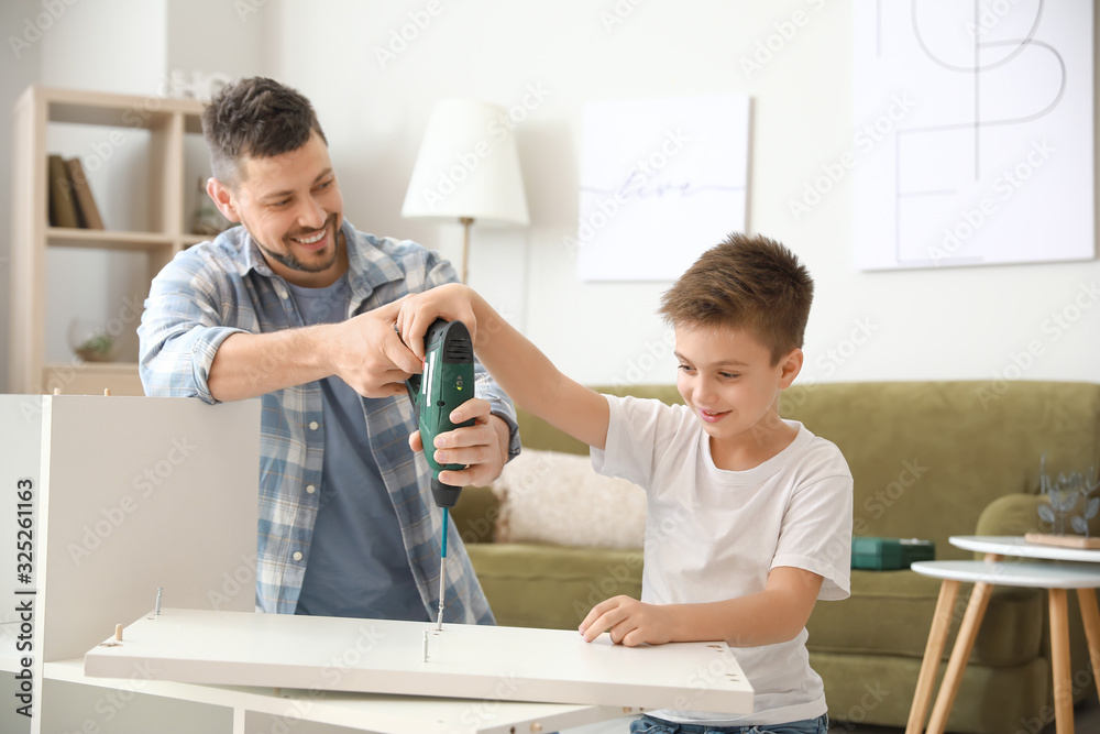 Father and his little son assembling furniture at home